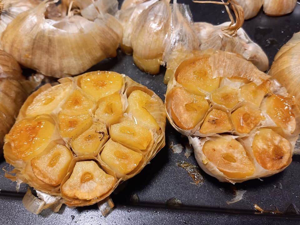 roasted garlic heads cut in half on an oven tray