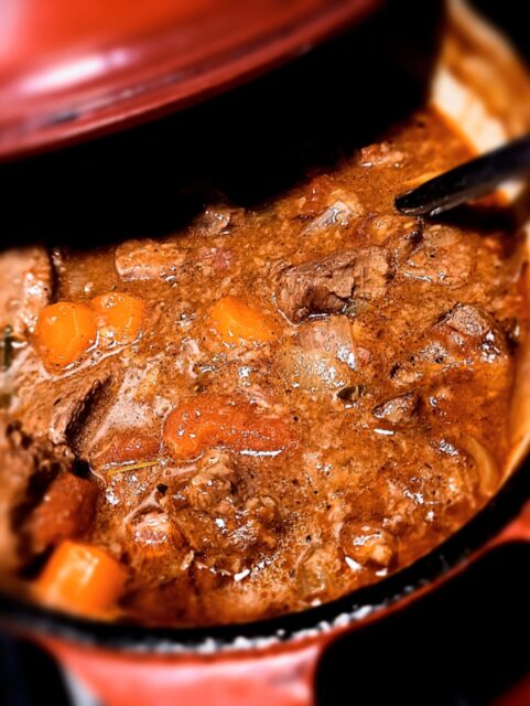 venison stew in a dutch oven with a ladle