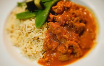 rabbit in tomato and saffron sauce. Steamed vegetables and rice on a plate
