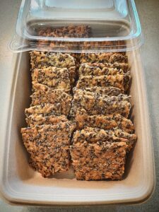 Crisp bread squares in a compostable tray with a plastic lid covering half the product