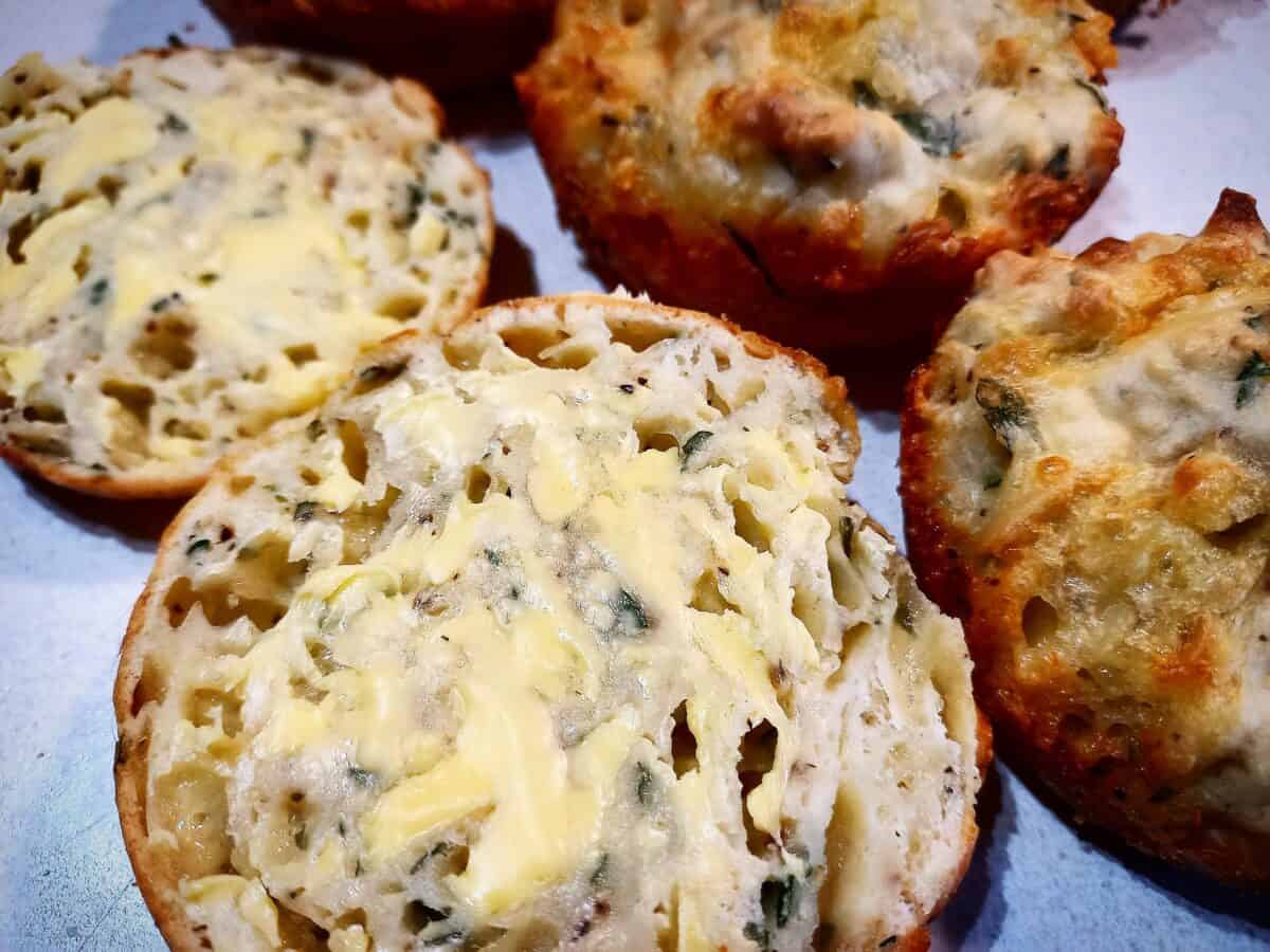 cheese and onion rolls cut in half spread with butter on a white plate