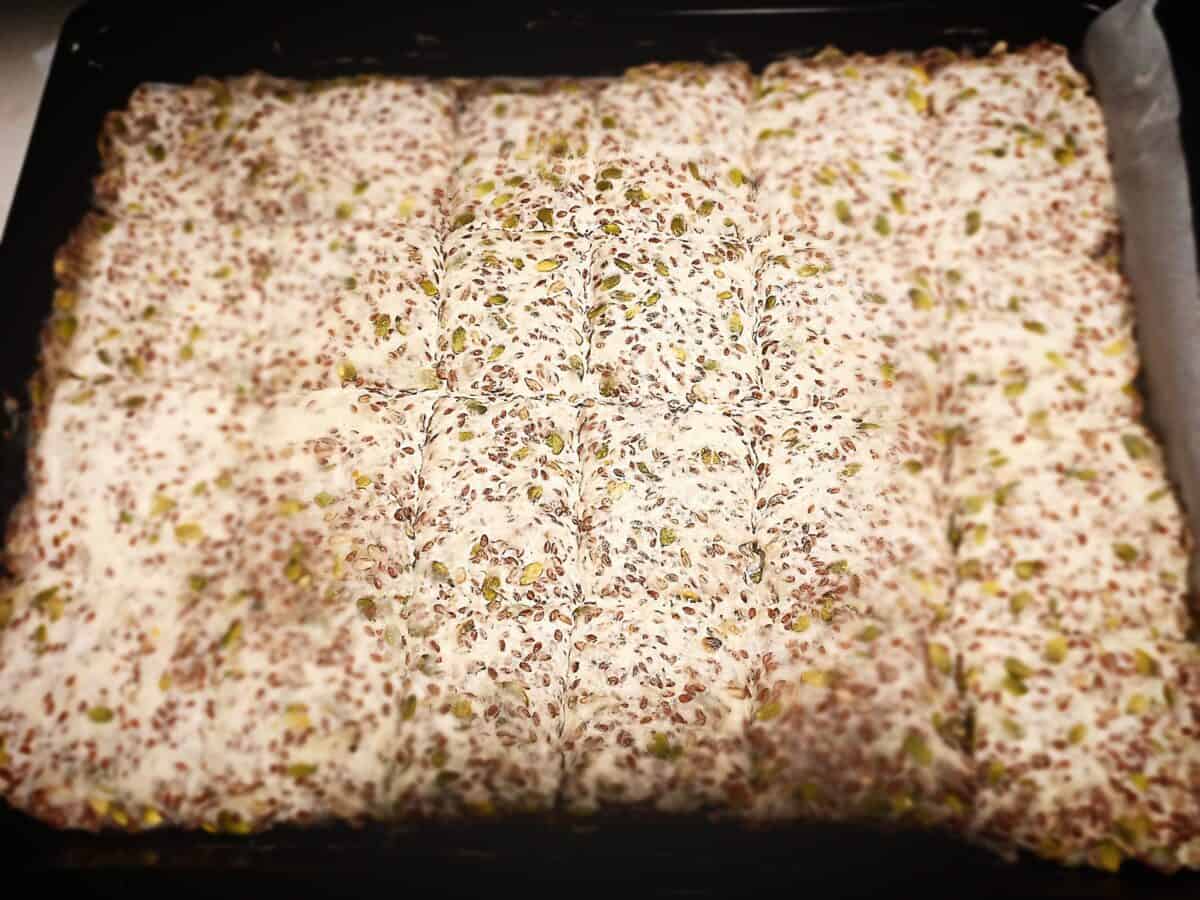 Uncooked Sunflower seed crisp bread, cut into squares, in an oven tray ready to go in the oven.