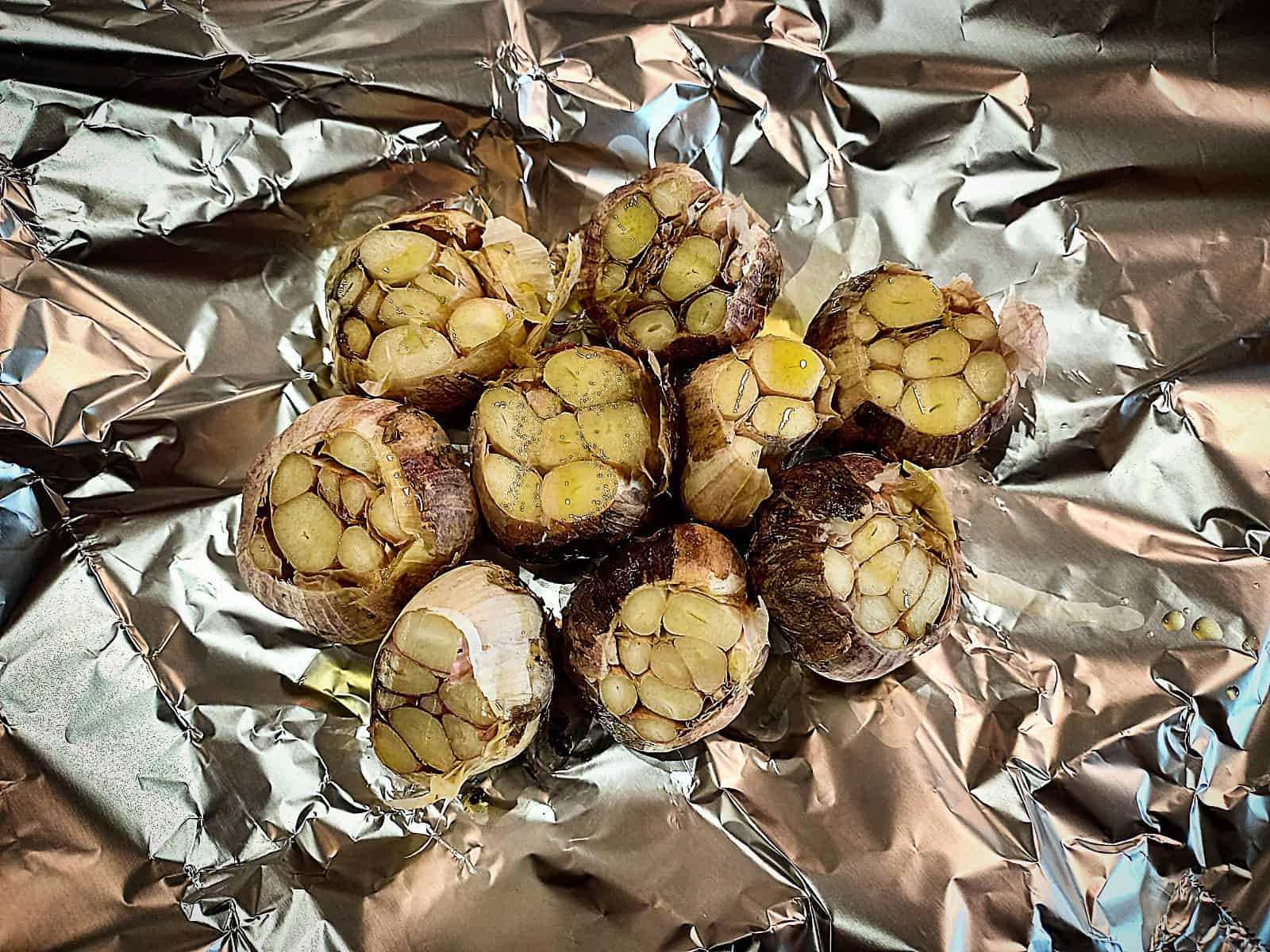 9 raw garlic heads with the top cut off, drizzled with olive oil on a piece of tin foil