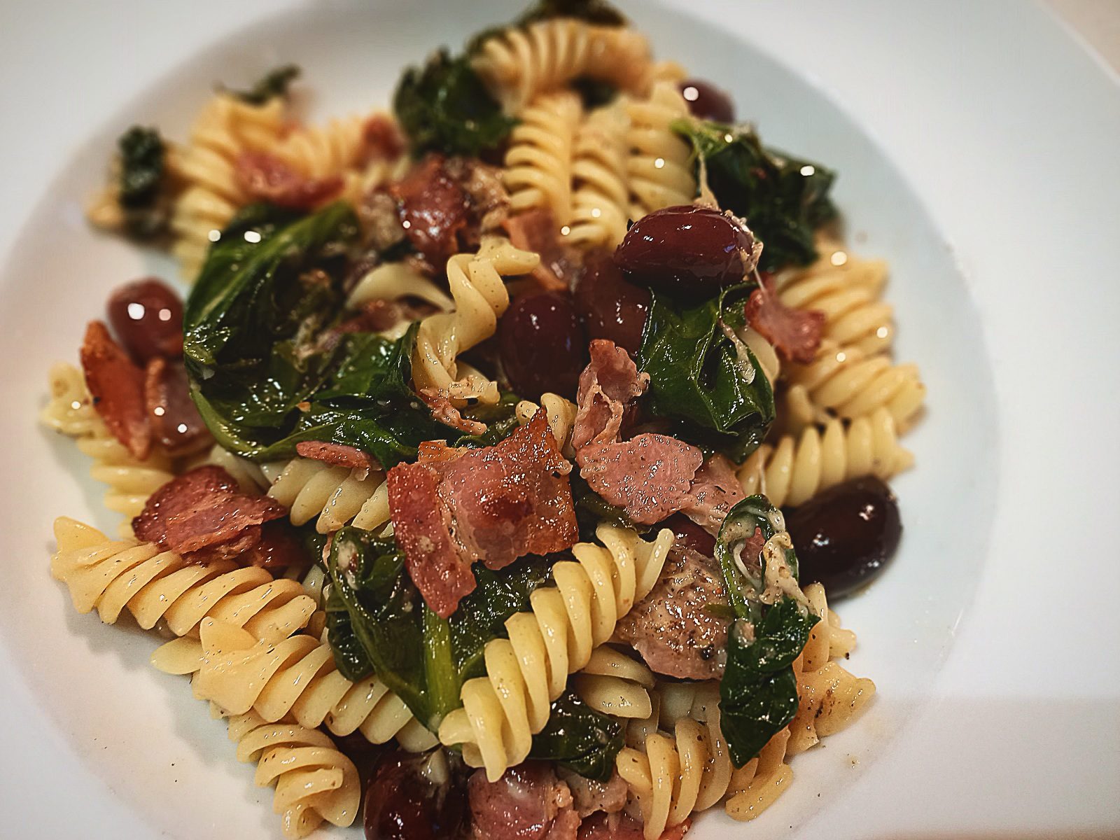Spirali pasta with spinach served in a white bowl plate
