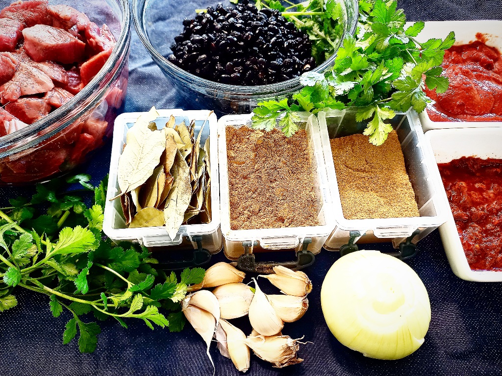 Ingredients to make black bean venison chili on a dark table