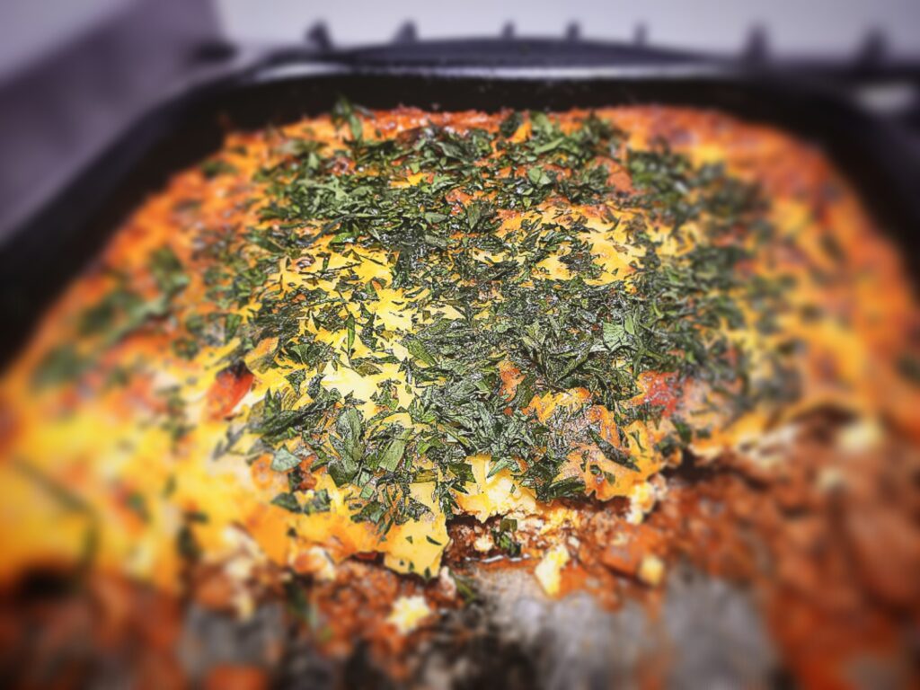 A close up picture of Lamb and courgette bake with a section cut out of it in a baking tray