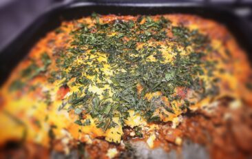 A close up picture of Lamb and courgette bake with a section cut out of it in a baking tray