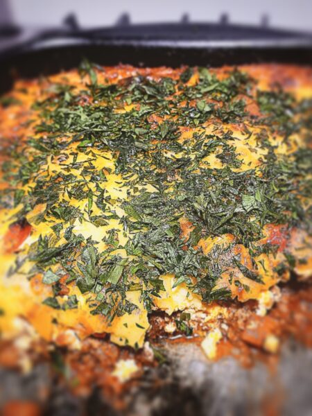 A close up picture of Lamb and courgette bake with a section cut out of it in a baking tray