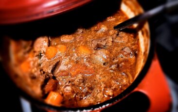venison stew in a red dutch oven with a ladle in it