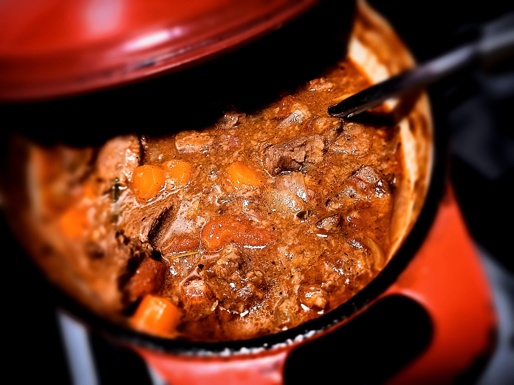 venison stew in a red dutch oven with a ladle in it