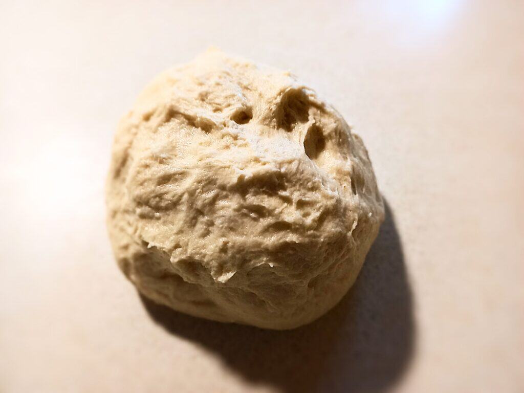 1 round pizza dough ball on a cream colored work bench