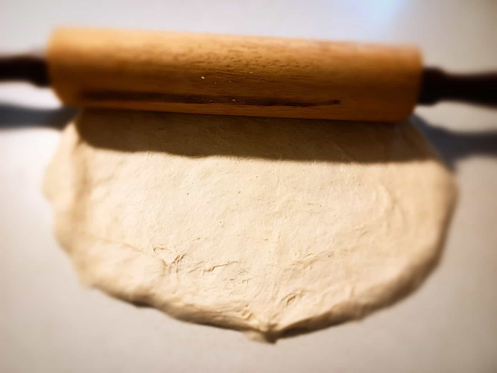 rolling out a round pizza base with a rolling pin