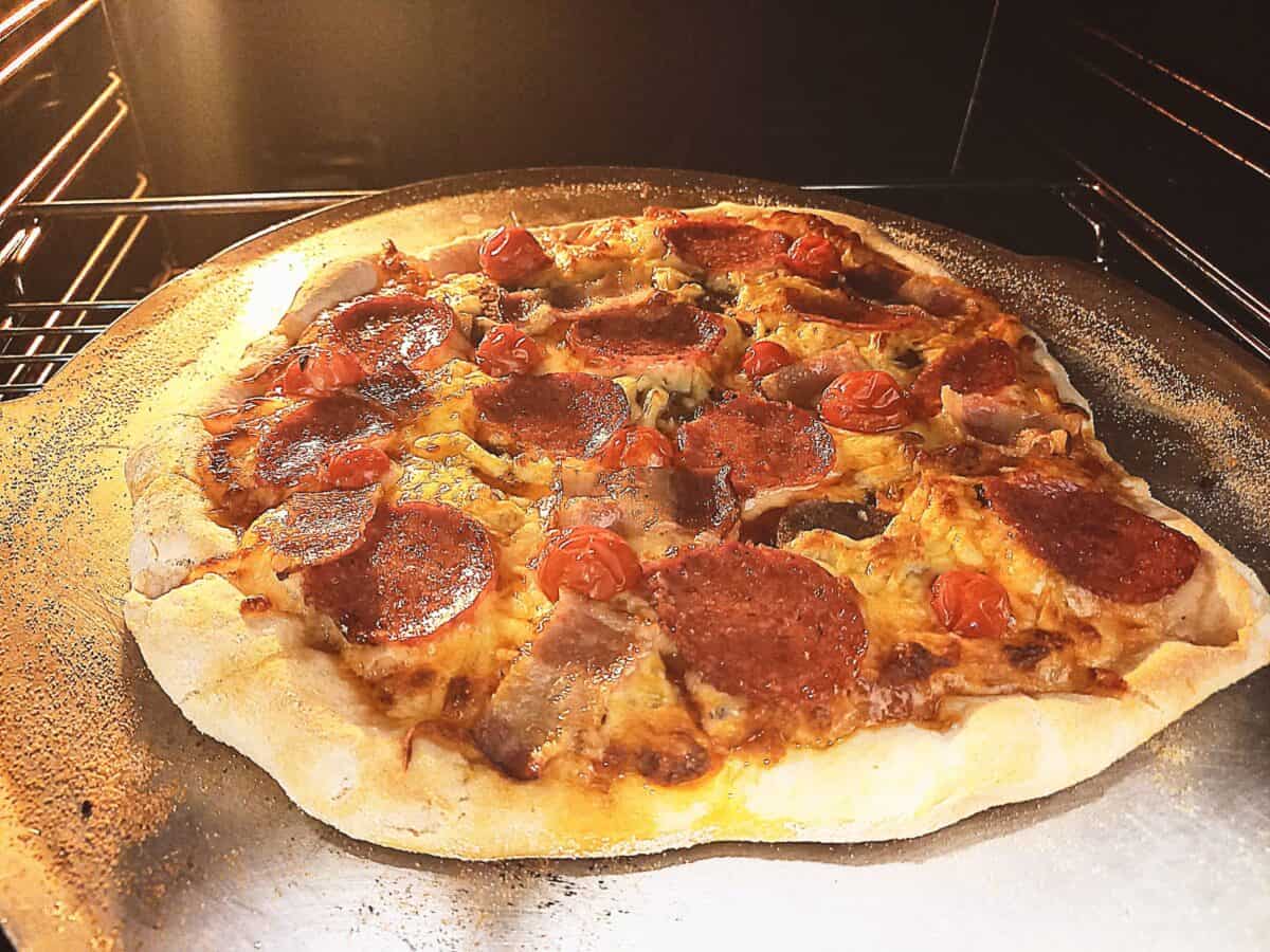 Pizza cooking on an aluminum tray in the oven