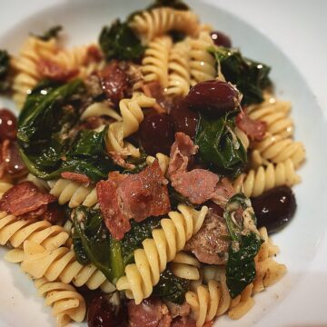 Spirali pasta with spinach served in a white bowl plate