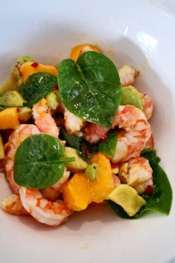 Prawn salad with mango and avocado served in a white bowl plate