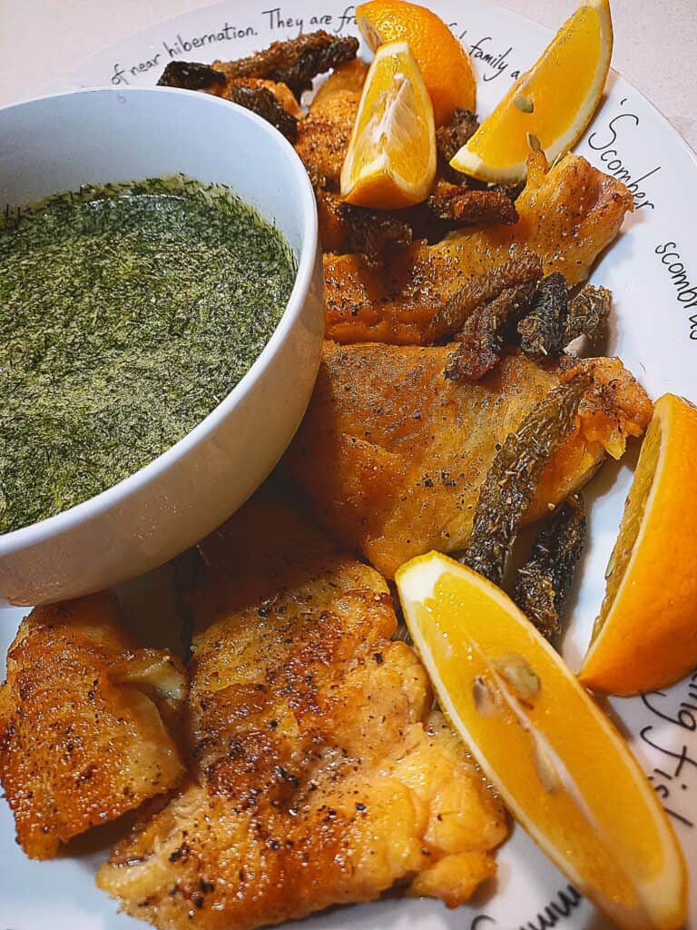 seared trout fillets with crispy skin, lemon wedges and dill and caper gremolata sauce on a platter