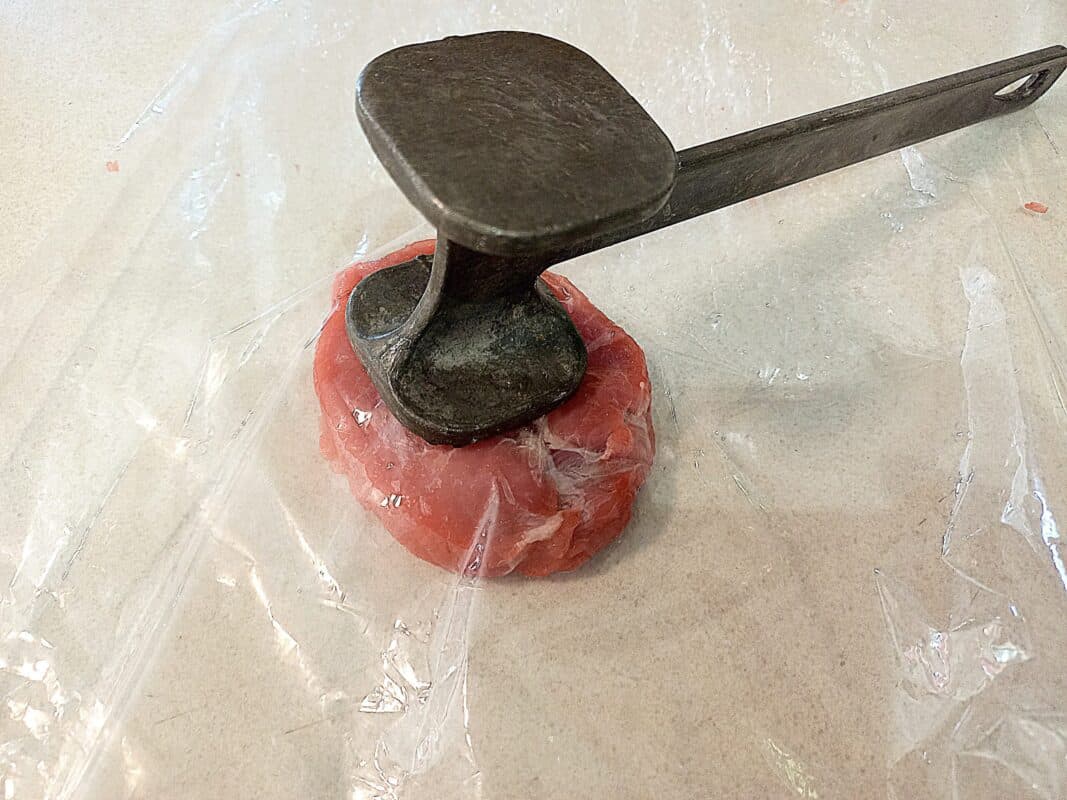 wild pork meat inside a plastic bag. Meat hammer on top of the meat
