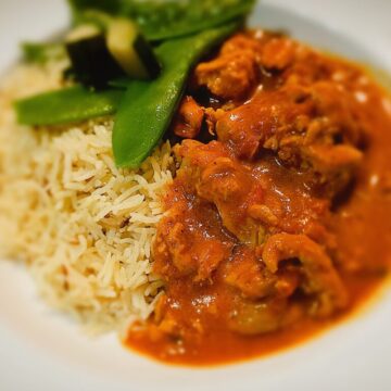 rabbit in tomato and saffron sauce. Steamed vegetables and rice on a plate