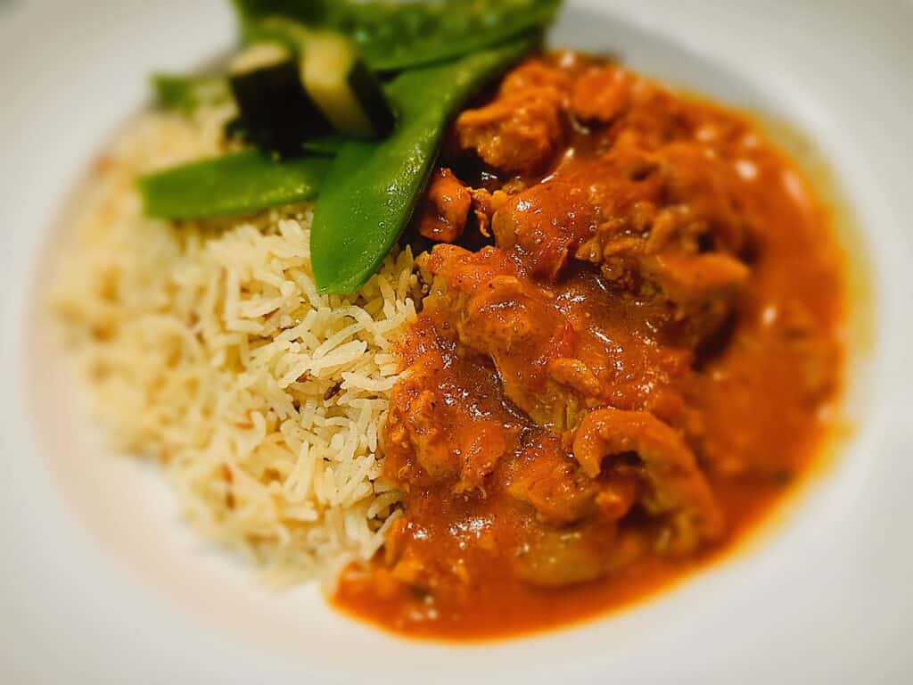 rabbit in tomato and saffron sauce. Steamed vegetables and rice on a plate