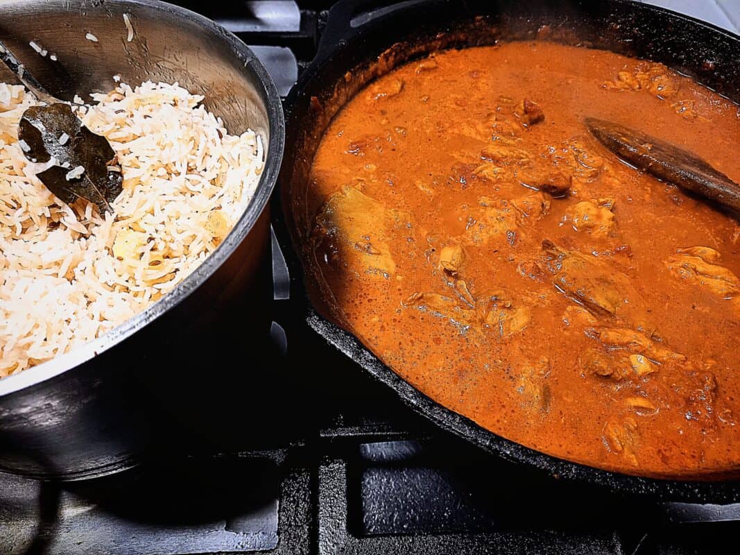 Rabbit in tomato and saffron sauce in a skillet pan. Steamed rice in a pot
