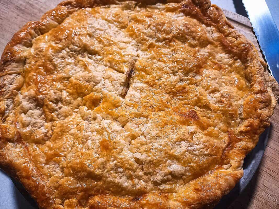 Bacon and egg pie on a chopping board. A knife laying on the chopping board.