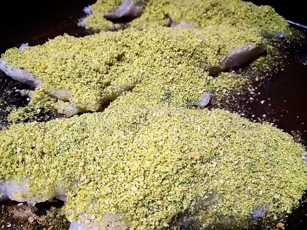 3 Raw blue cod fillets on a baking tray with herb crust on top