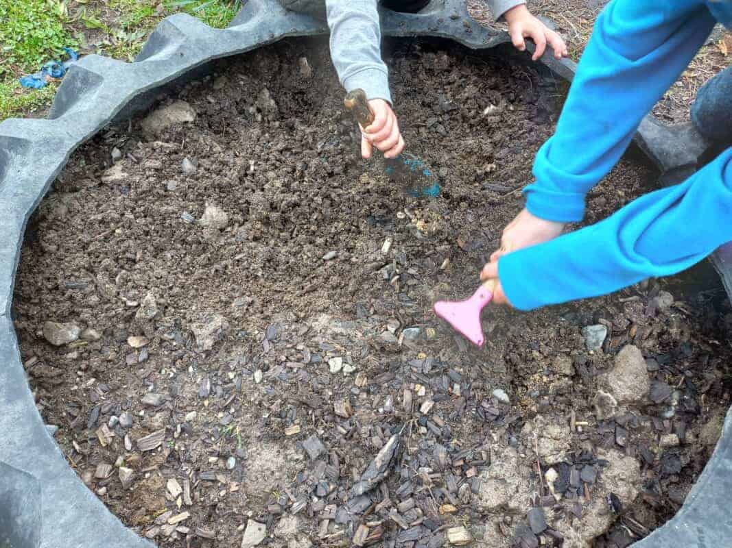 Two kids are digging in the tractor tyre garden bed