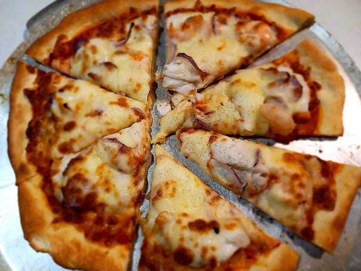 Freshly cooked pizza on a pizza tray cut in to 8 pieces