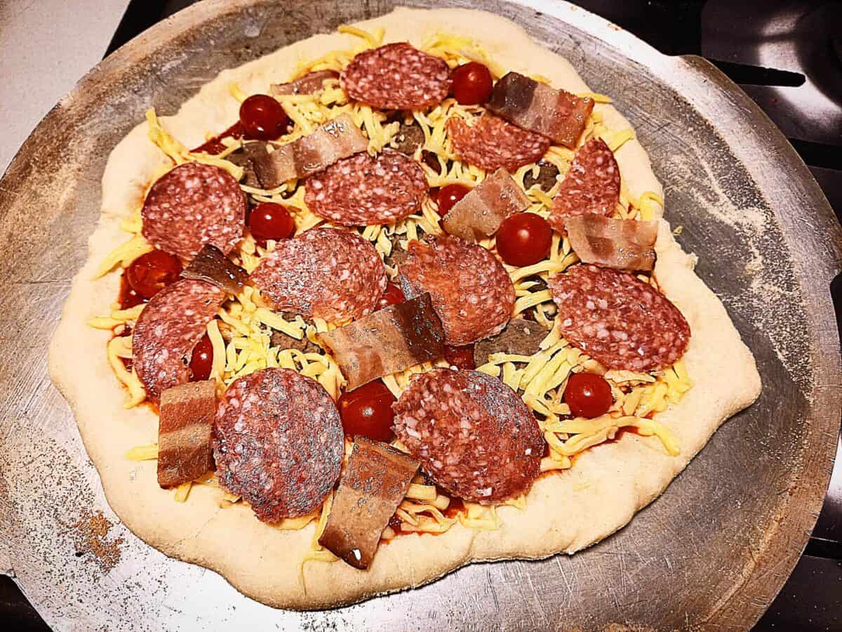 uncooked pizza on a pizza tray ready to go in the oven