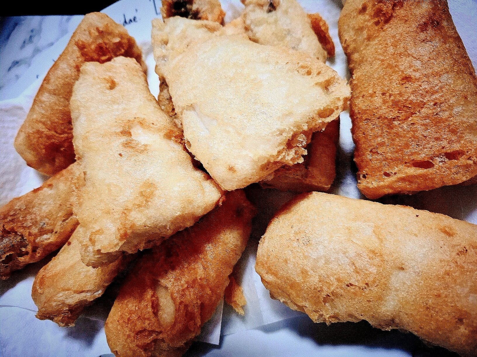 10 pieces of tempura fish resting on paper towel.