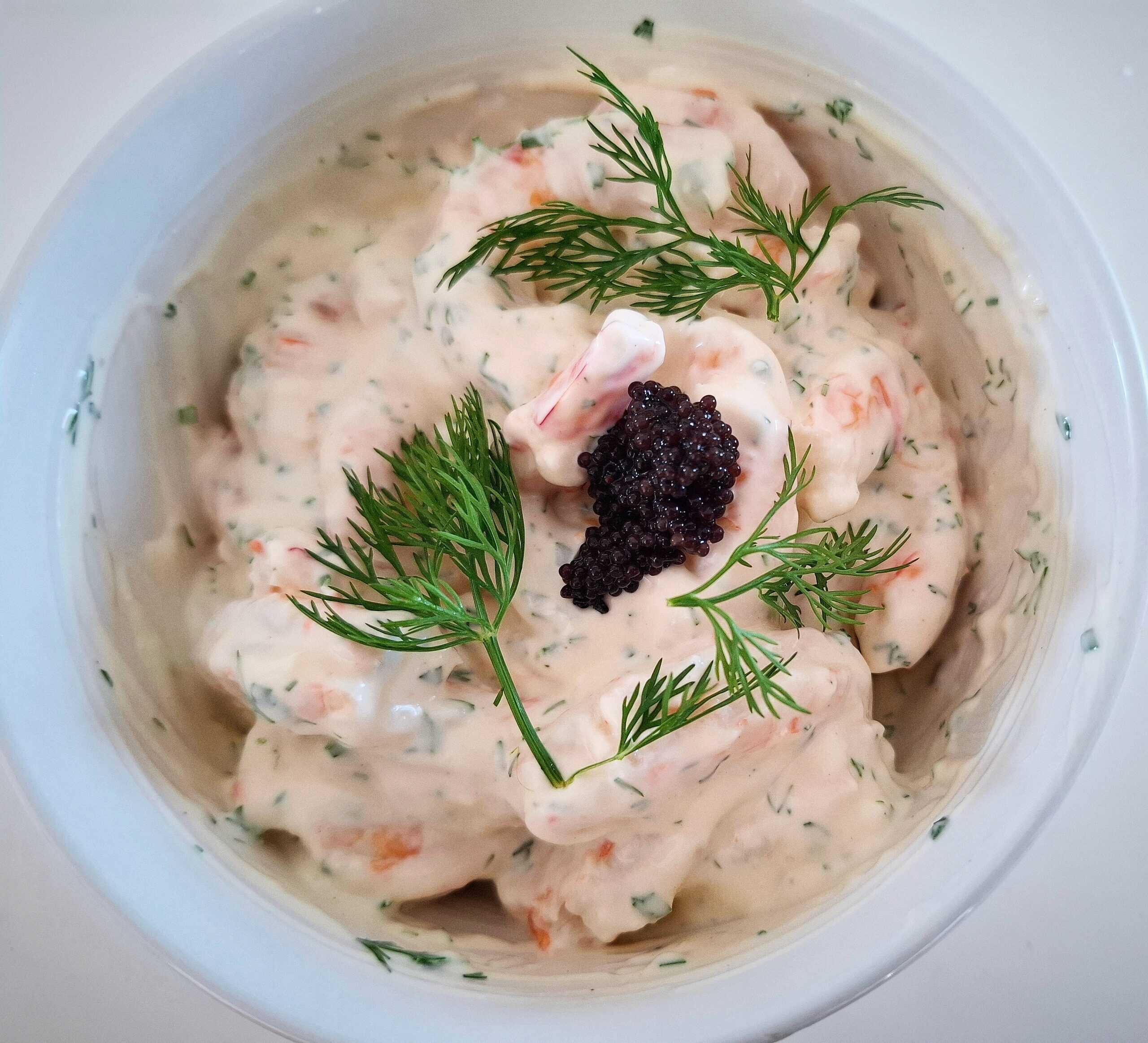 prawn shrimp skagen with lump fish caviar and fresh dill on top in a white bowl on a white table