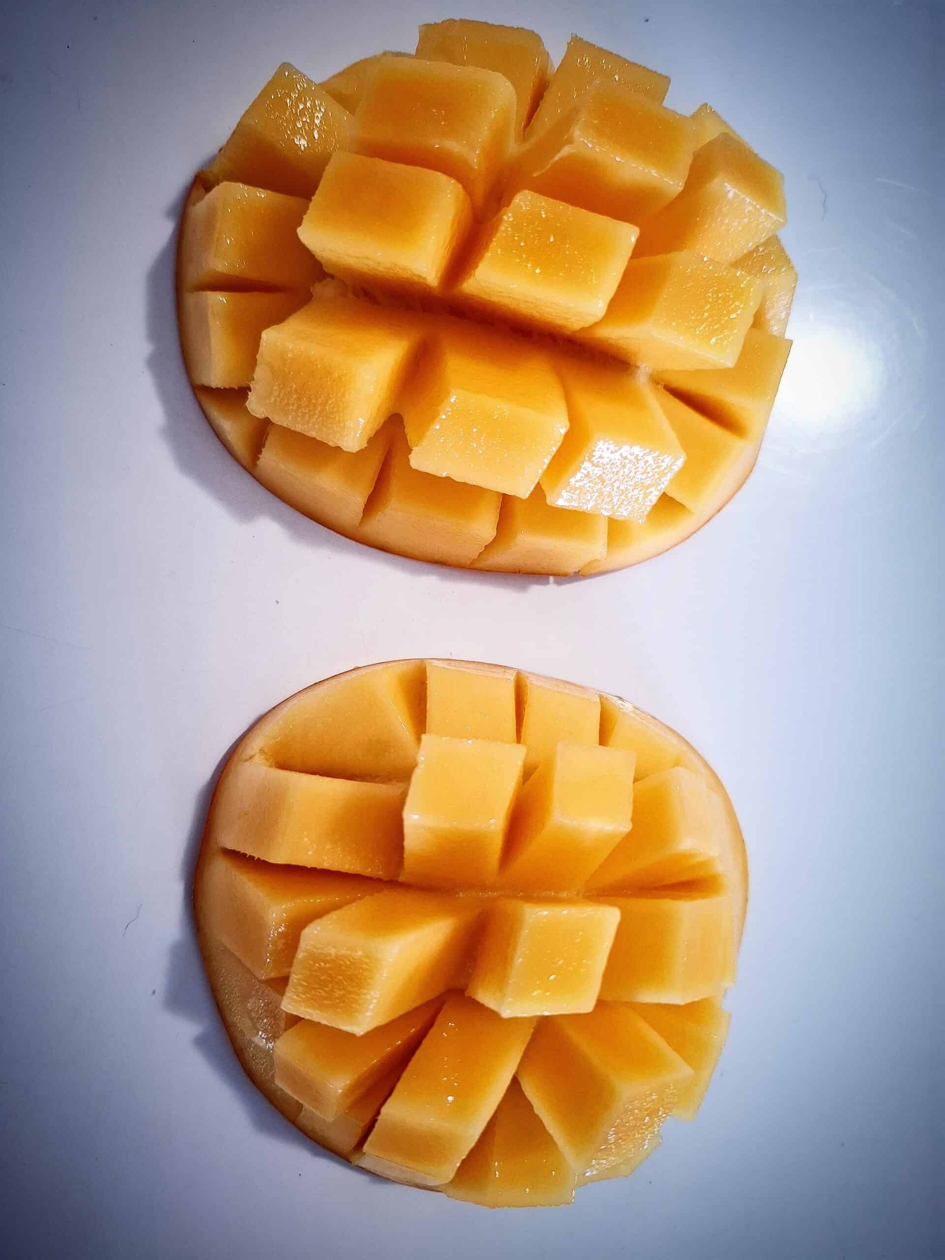 Two mango cheeks with the criss cross pattern flesh inside out by pushing on the skin.