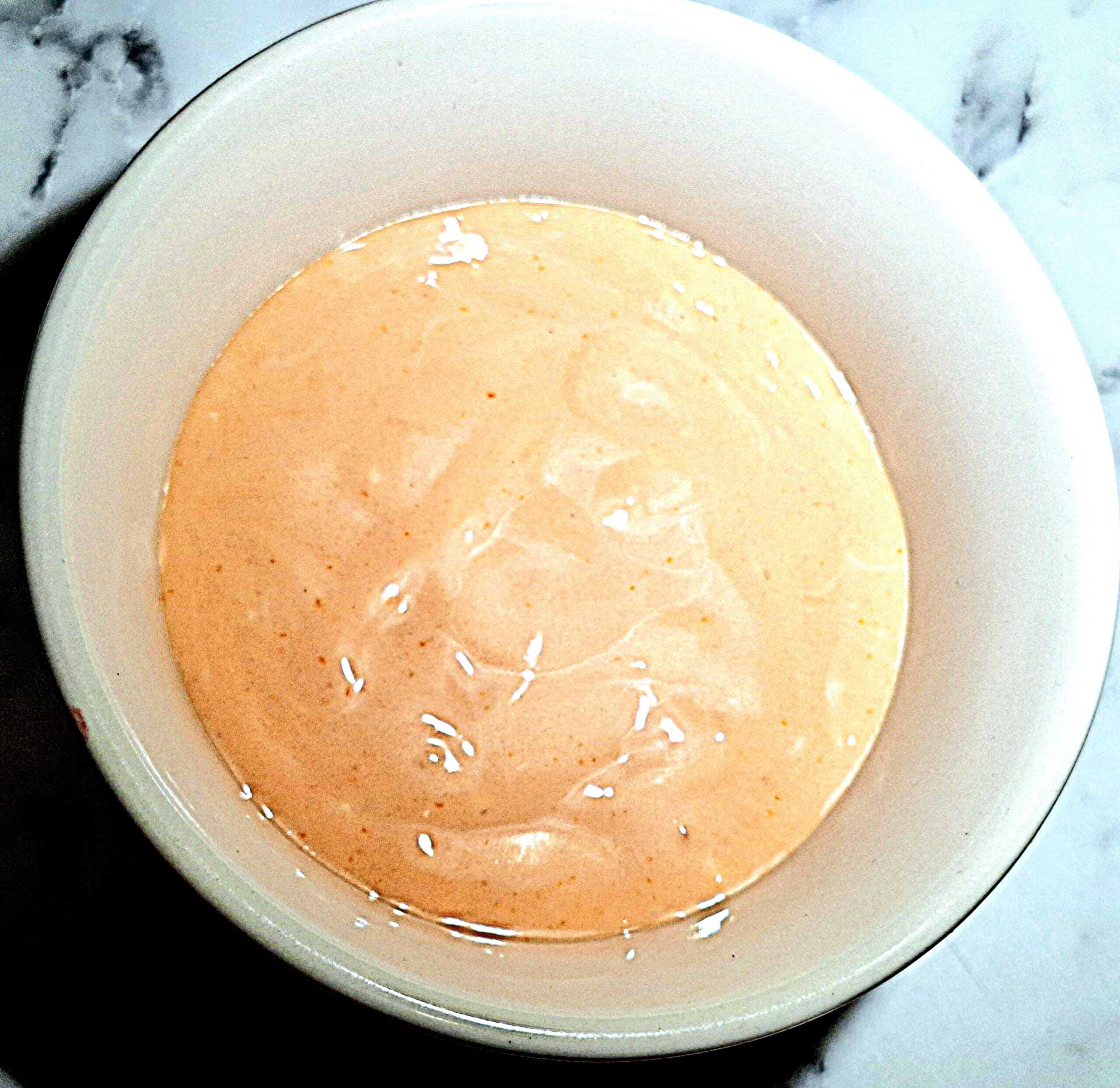 Seafood cocktail sauce in a round ramekin on a marbled bench top