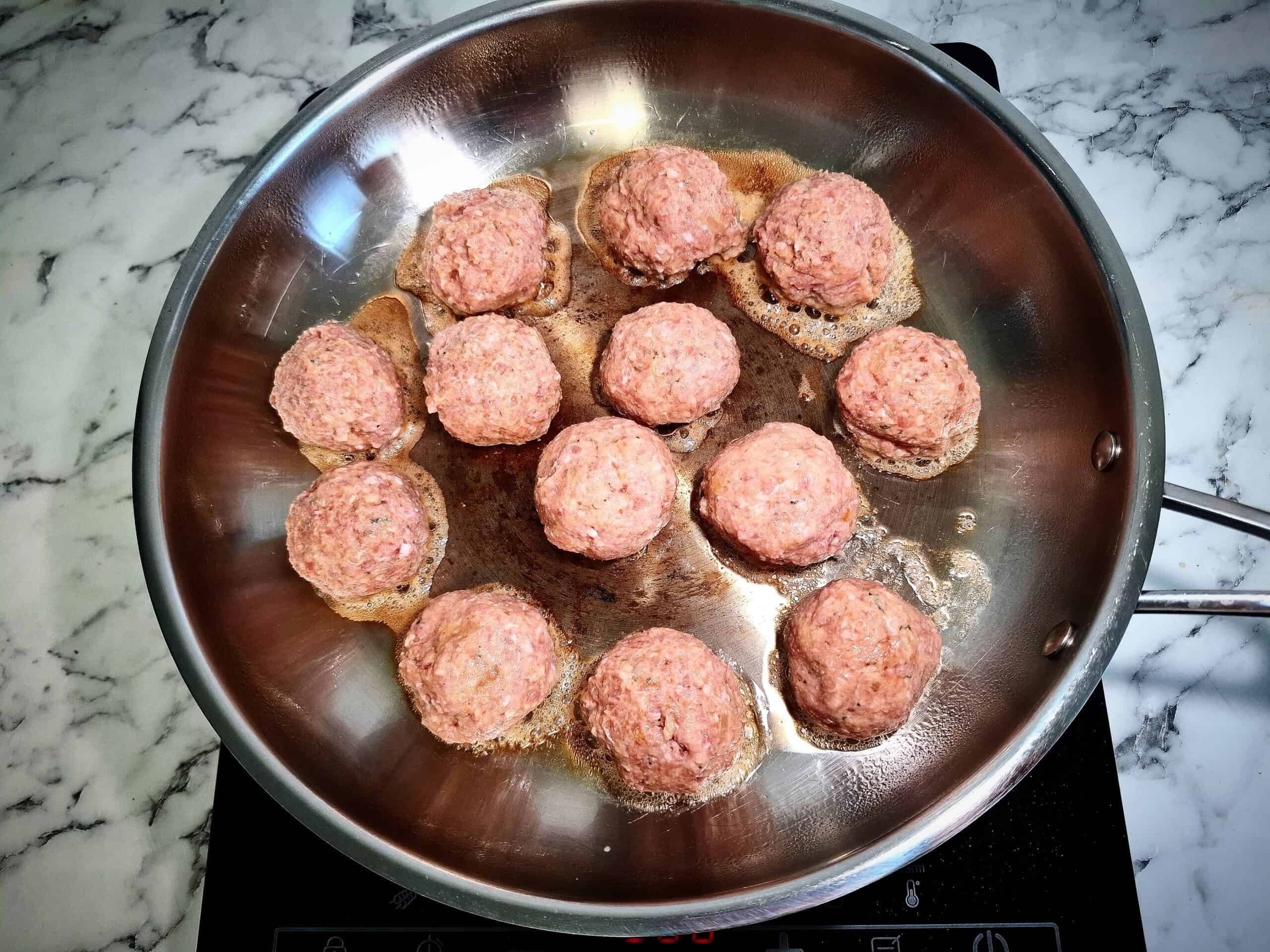 Frying meatballs in a stainless steel frying pan