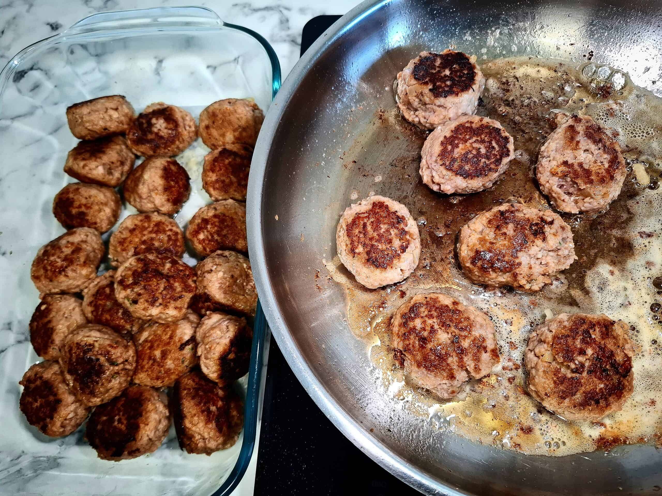 Frying meatballs until golden brown and caramelized in a stainless steel frying pan and transferring them to a glass oven proof dish
