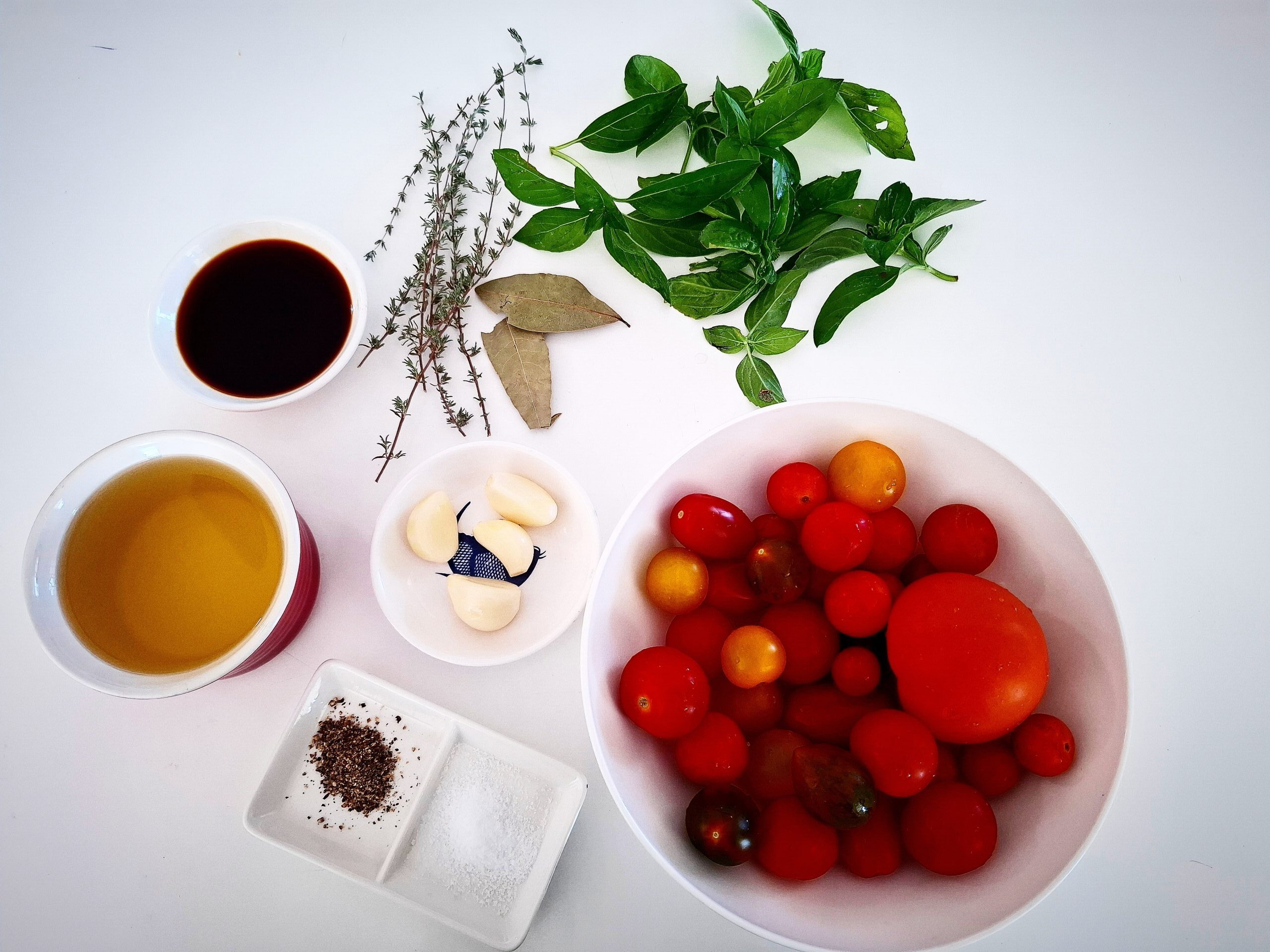 Ingredients needed to make tomato confit on a white tabletop