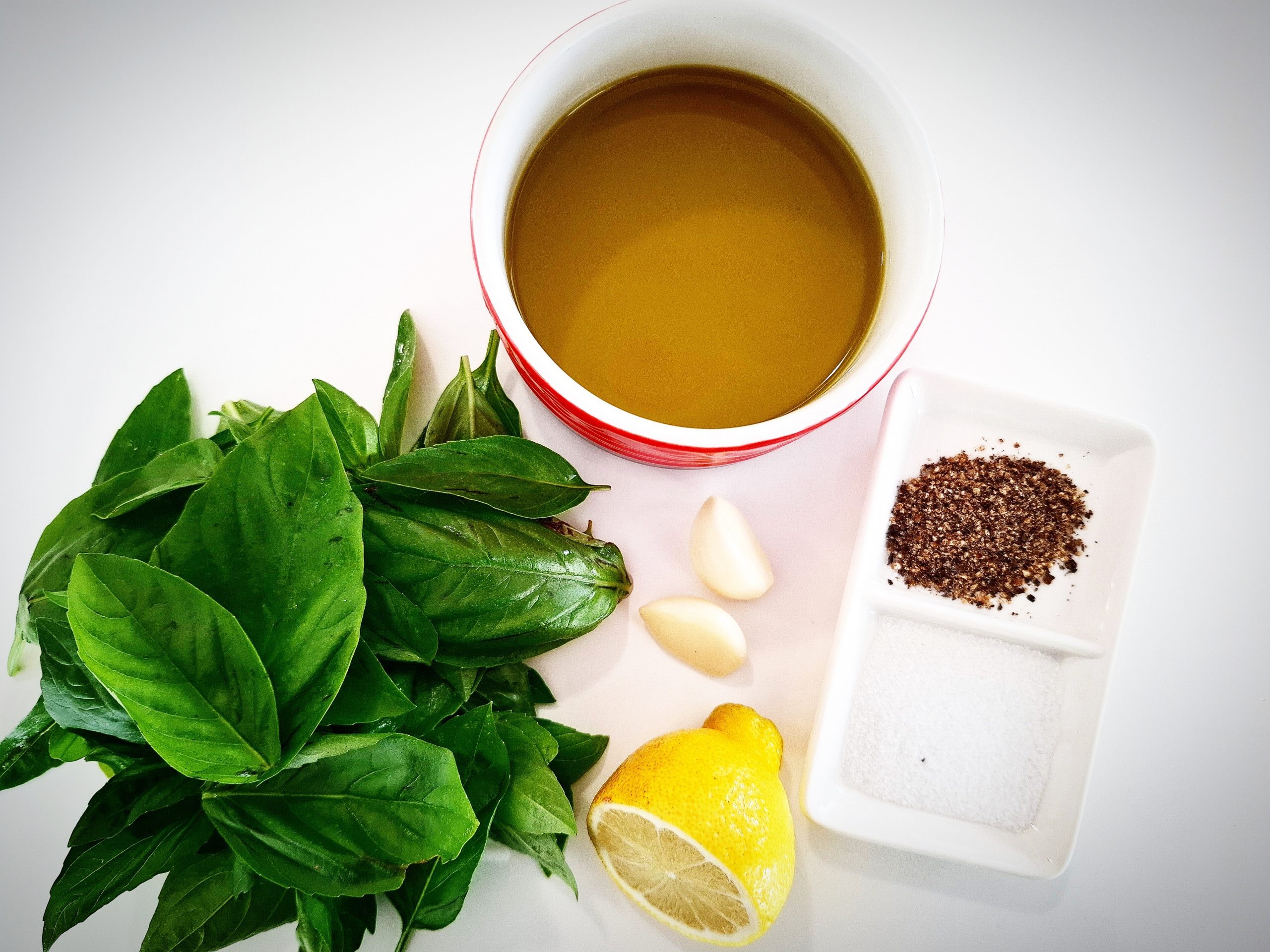 Ingredient needed for Basil, lemon, garlic dressing on a white table top