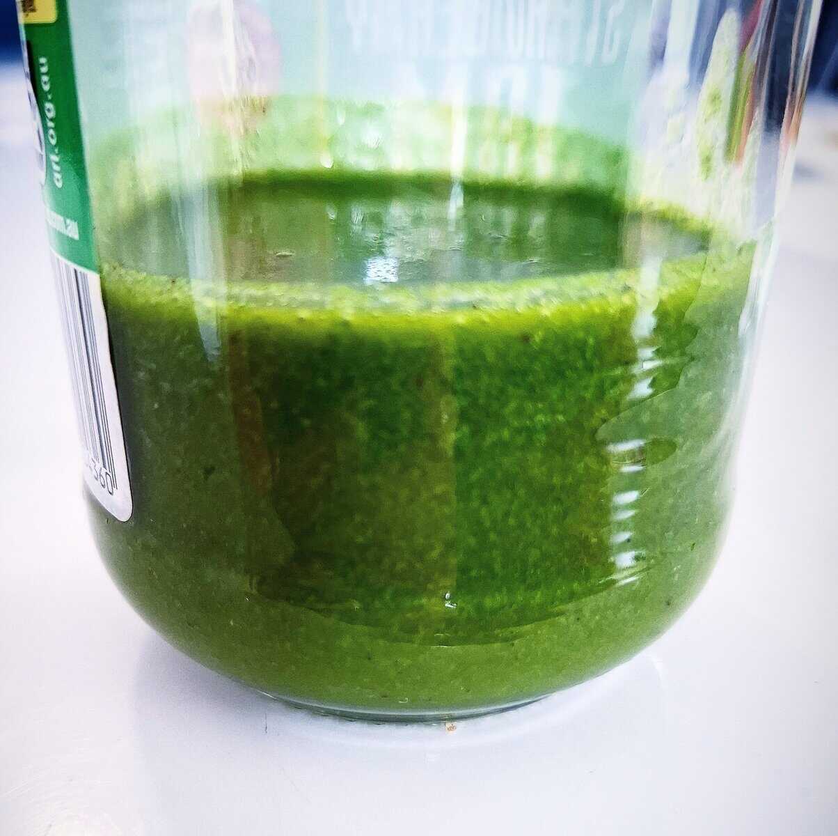 Basil garlic oil in a recycled glass jar on a white table