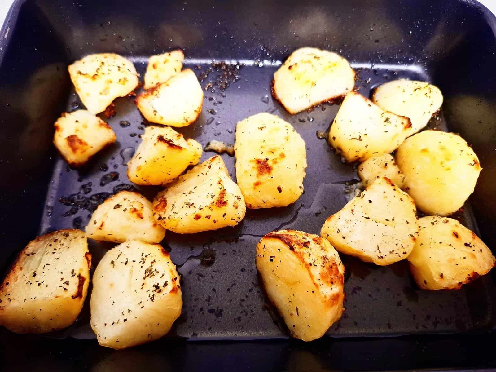 Roasted potatoes in a black oven tray