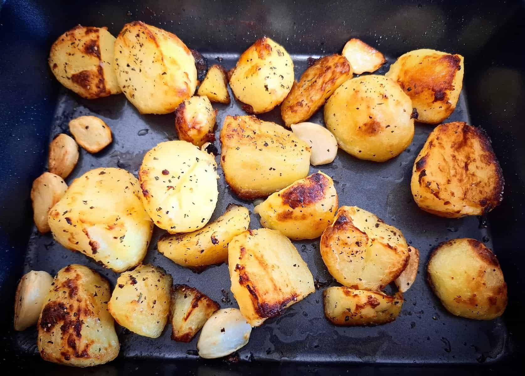 Mediterranean roasted potatoes in a black oven tray