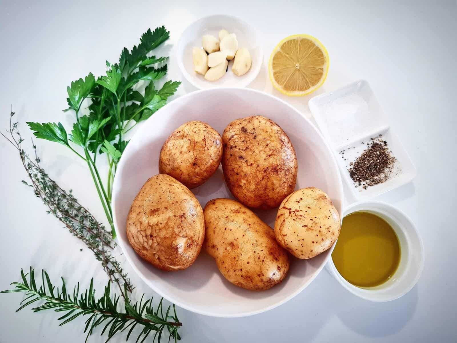 All the ingredients for Mediterranean roasted potatoes on a white table