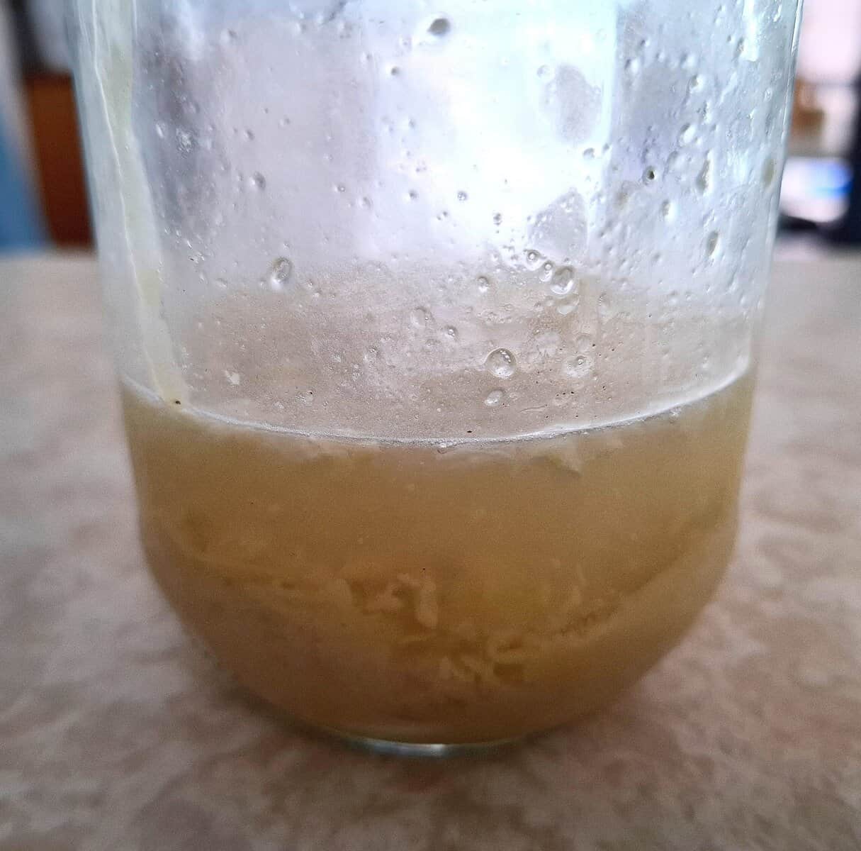 Ingredients for sesame lemon garlic dressing in a glass jar on a table
