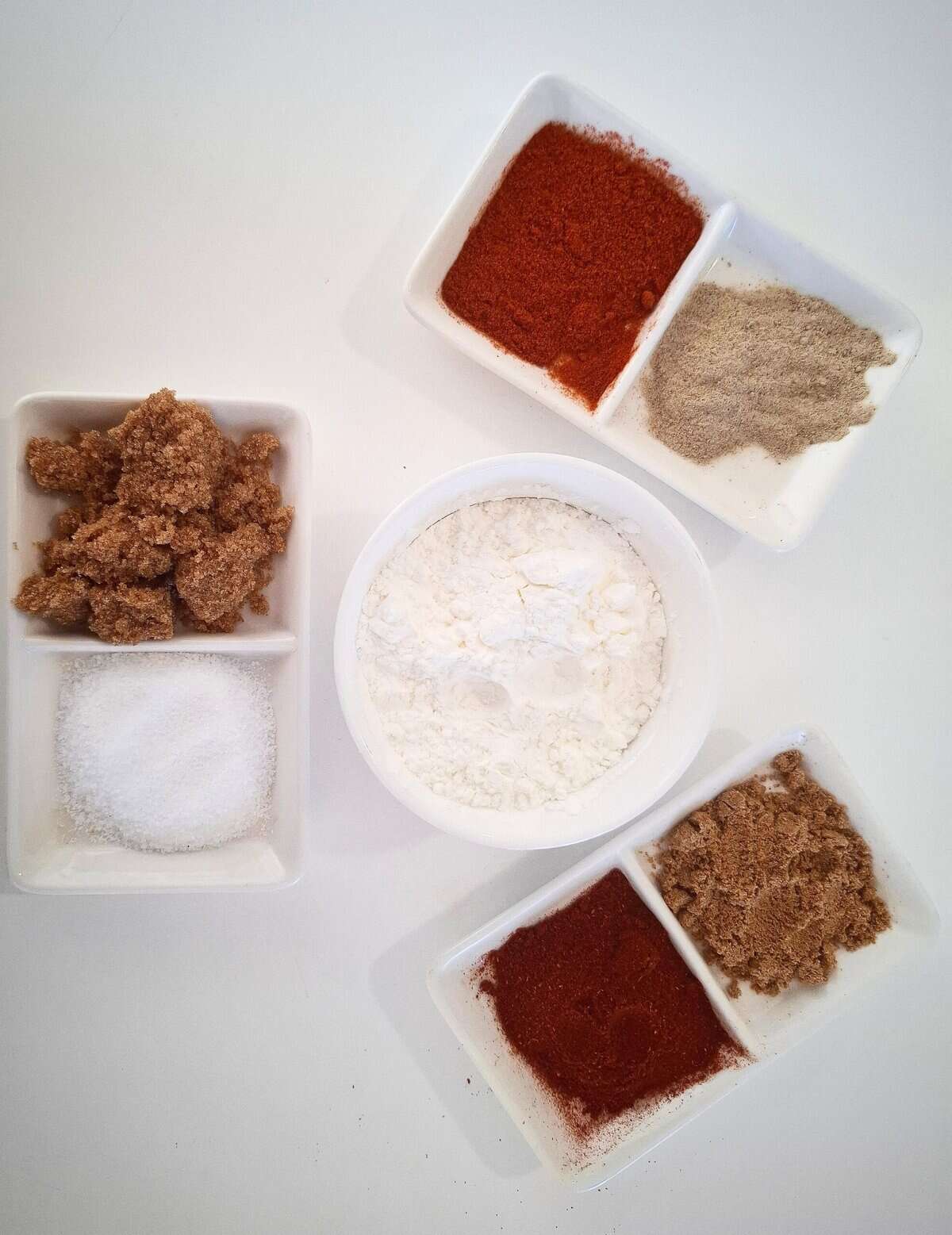 All the ingredients for spice coating is presented in white ramekins on a white table