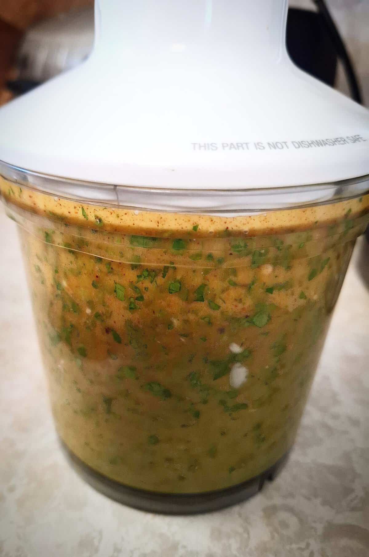 Chimichurri sauce red being chopped in a clear blender base.