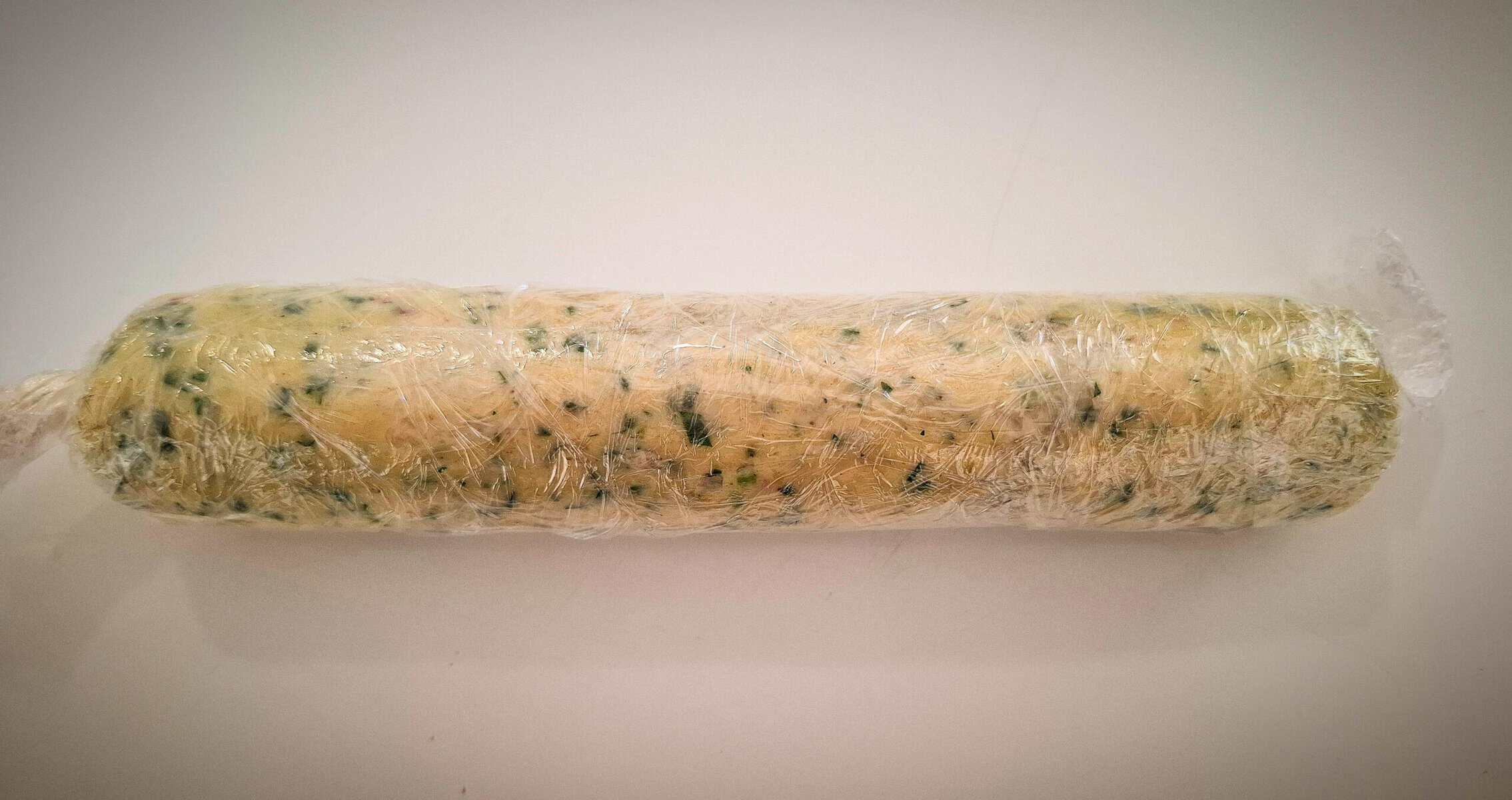 Garlic ginger butter rolled up to a log in cling wrap on a white bench top