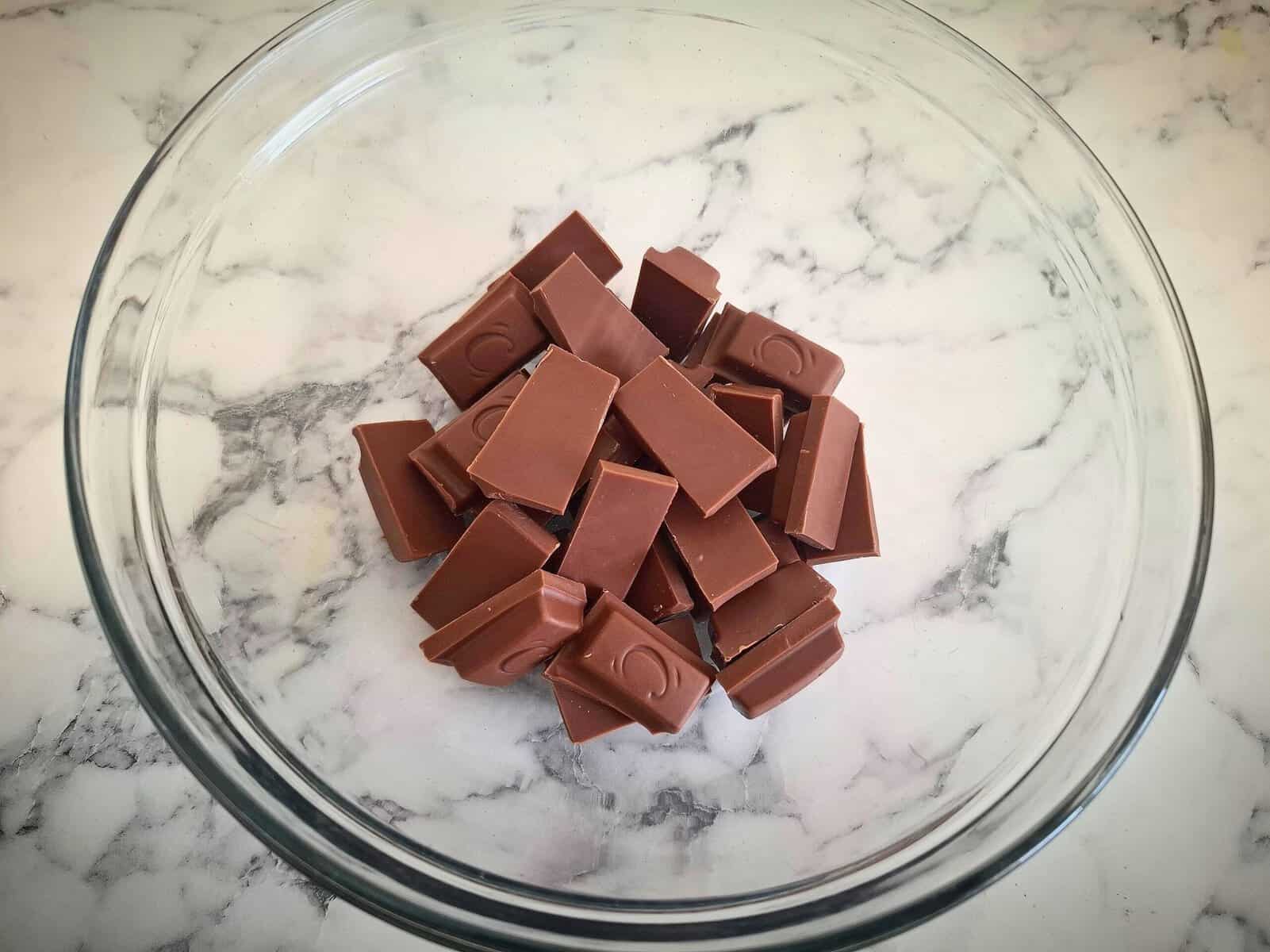 Rectangular chocolate pieces in a glass bowl on a marbled bench top