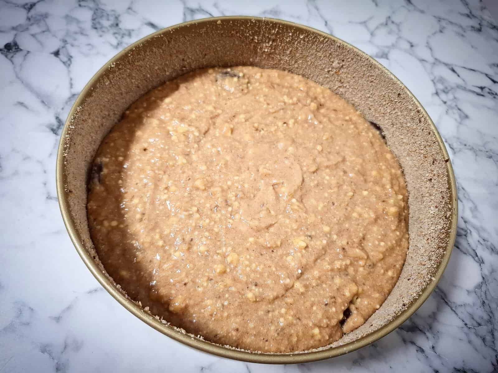 A breaded cake tin half filled with banana chocolate cake mixture
