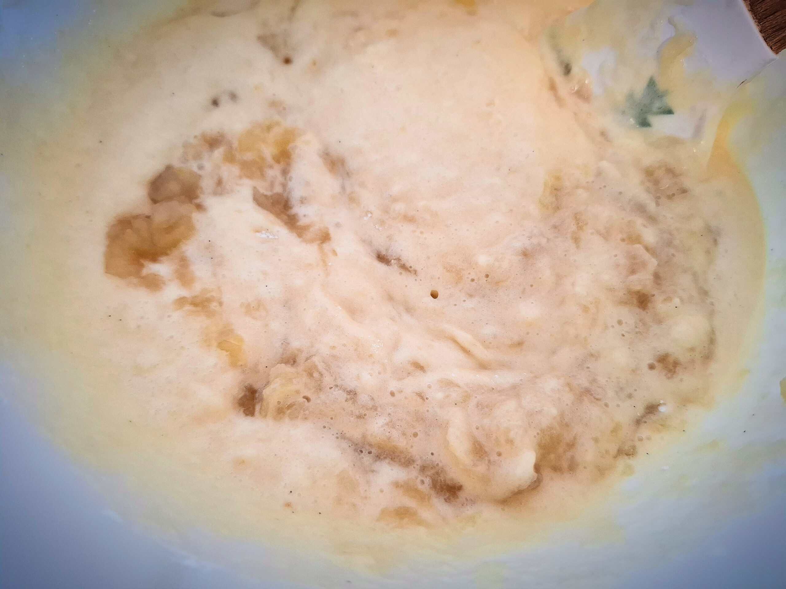 Apple and cinnamon being added to the cake batter in a white bowl.