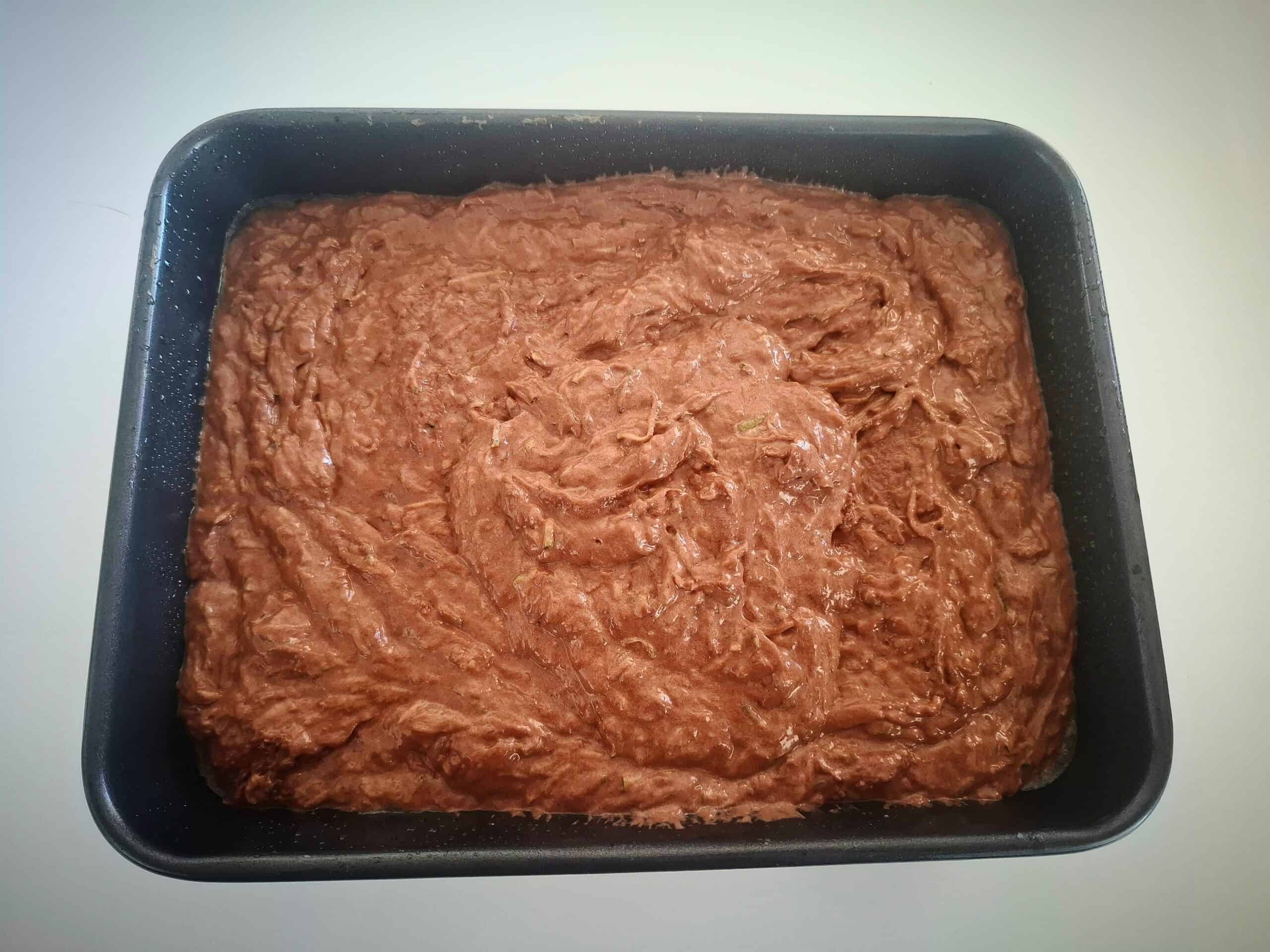 Courgette and chocolate cake batter in a black rectangular oven tray