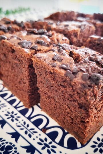 Courgette and chocolate cake cut into square pieces served on a blue and white platter